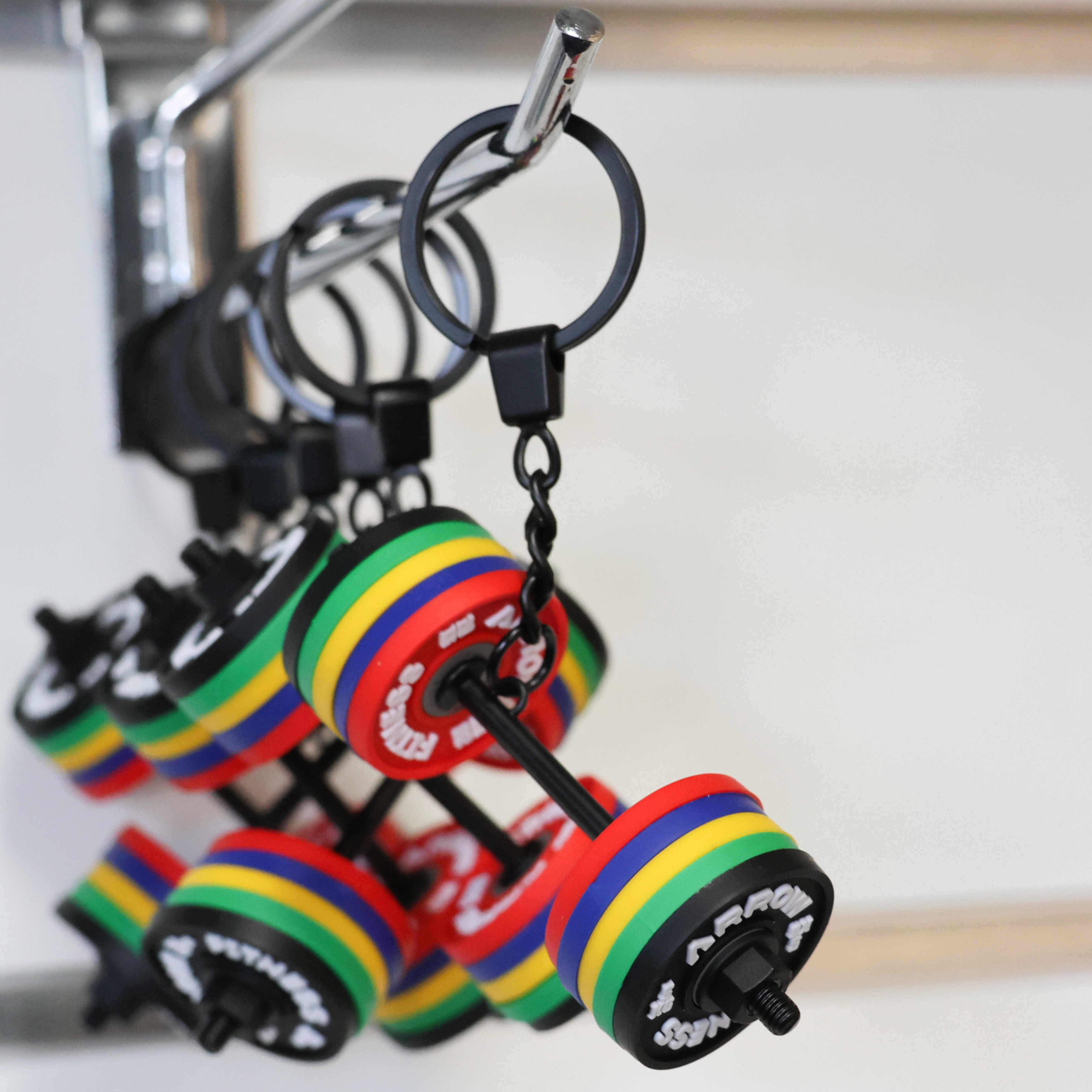 Colorful dumbbell-shaped keychains hanging on a keychain holder.