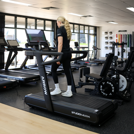 Treadmill in a gym setting with various exercise equipment around.