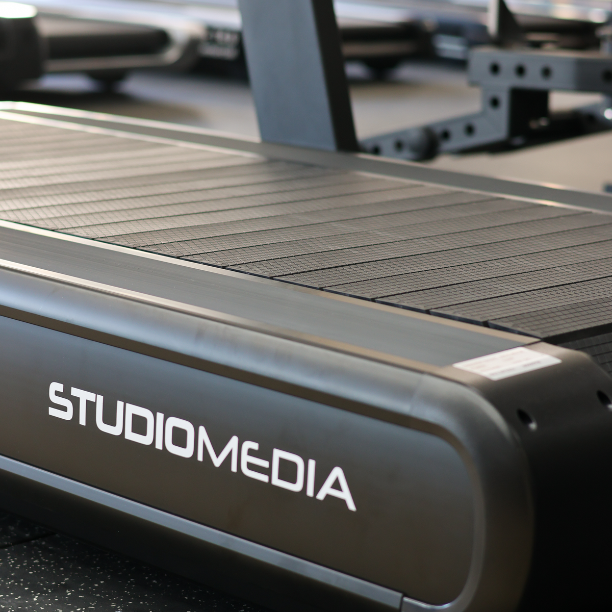 Close-up of a treadmill with 'STUDIOMEDIA' branding on a blurred background