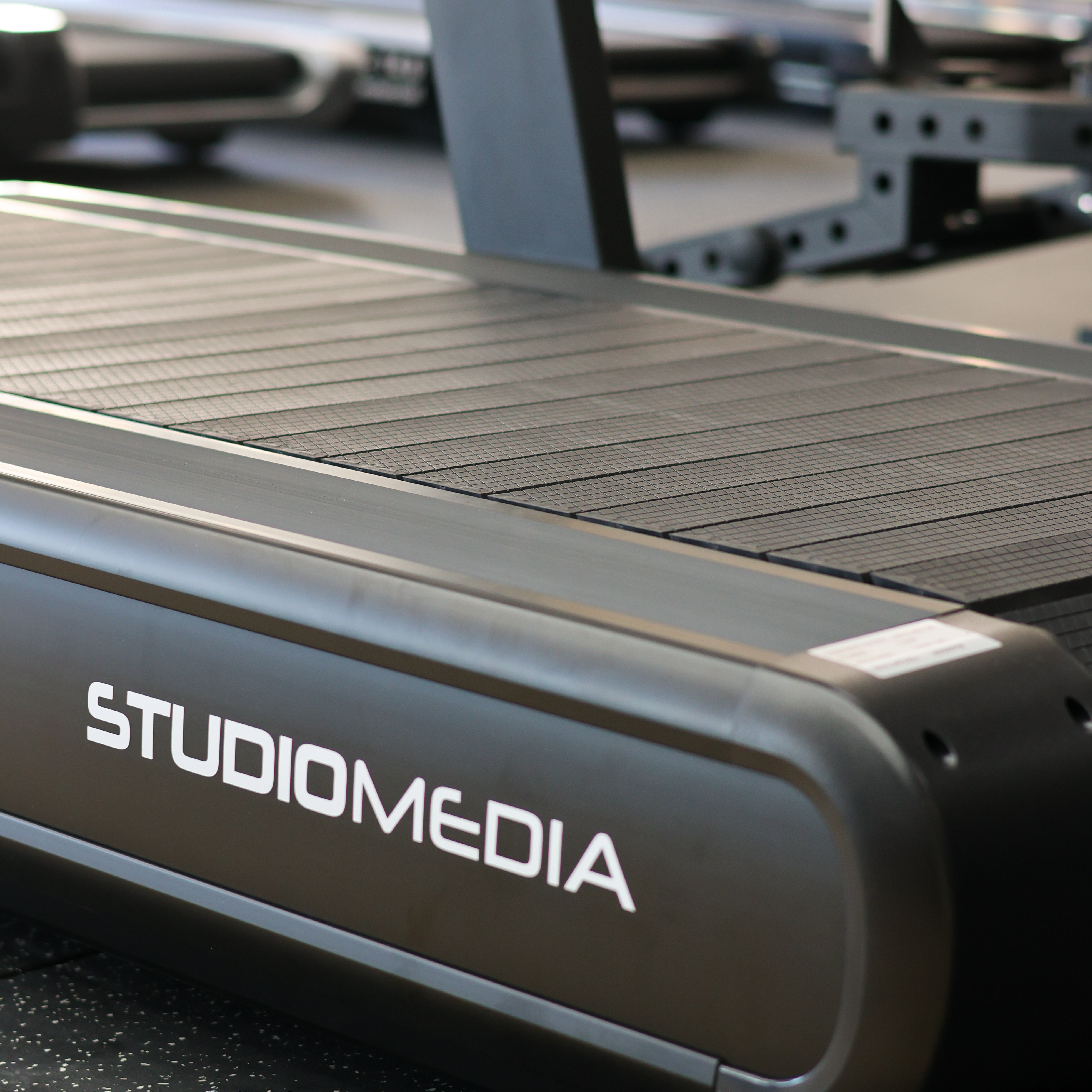 Close-up of a treadmill with 'STUDIOMEDIA' branding on a blurred background