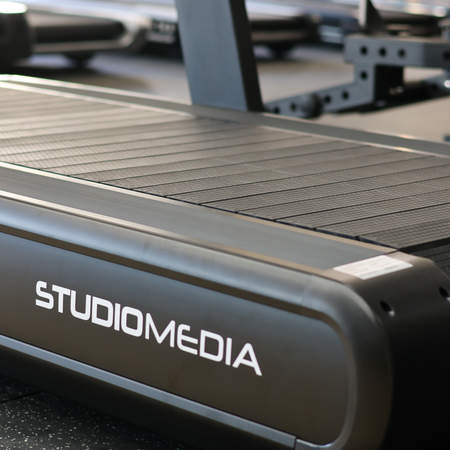Close-up of a treadmill with 'STUDIOMEDIA' branding on a blurred background