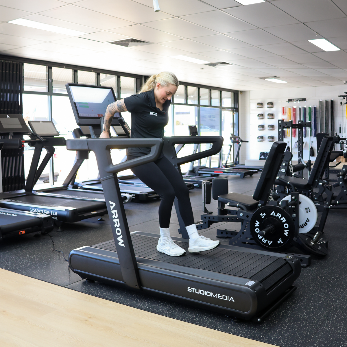 Person using a treadmill in a gym setting with 'StudioMedia' branding.